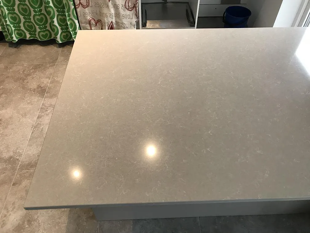 Stor köksö med polerad bänkskiva i Technistone Noble Ivory White, krämvit kvartskomposit med diskret ådring, i ett kök i Svalöv.