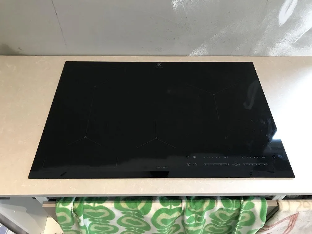 Svart Electrolux induktionshäll infälld i en polerad bänkskiva av Technistone Noble Ivory White i ett kök i Svalöv.