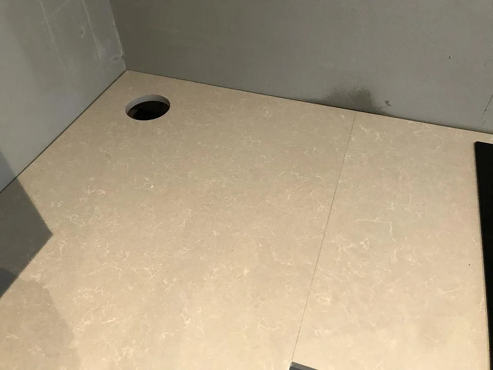 Hörn av en köksbänk i Technistone Noble Ivory White med förborrat hål för blandare, polerad yta i ett kök i Svalöv.