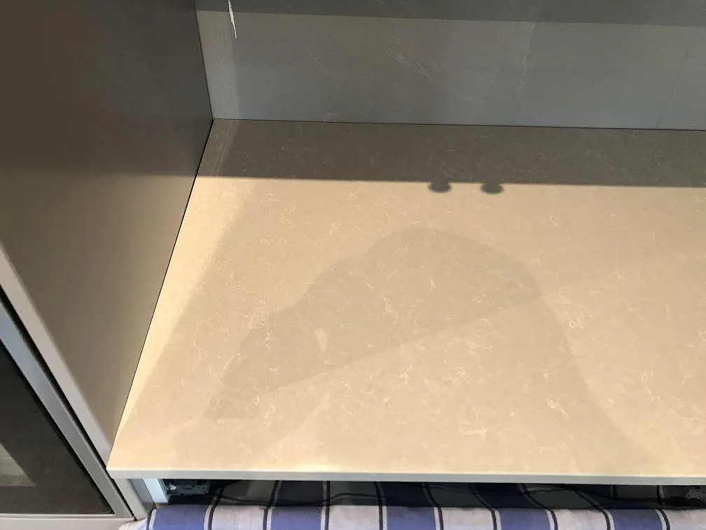 Polerad köksbänkskiva i ljus Technistone Noble Ivory White med spegelblank yta i ett kök i Svalöv.