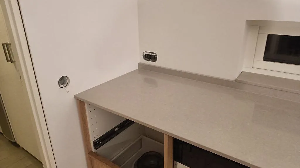 Polerad Technistone Noble Ivory White köksbänkskiva med låg stänkkant och ljus stenstruktur vid fönsterhörnet i Trelleborg.