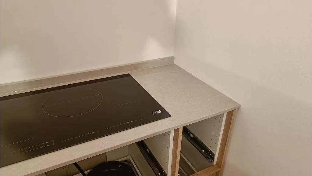 Sidovy av polerad Technistone Noble Ivory White bänkskiva med häll och rak avslutning mot vägg i Trelleborg.