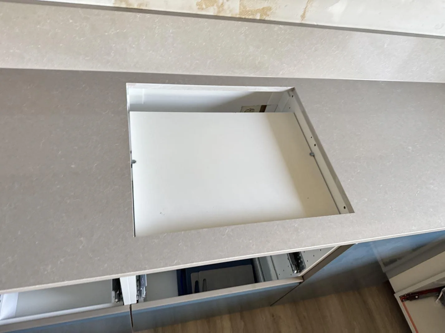 Detalj av hällurtag i polerad Technistone Noble Ivory White, ljus kvartskomposit monterad på köksstommar i Trollhättan.
