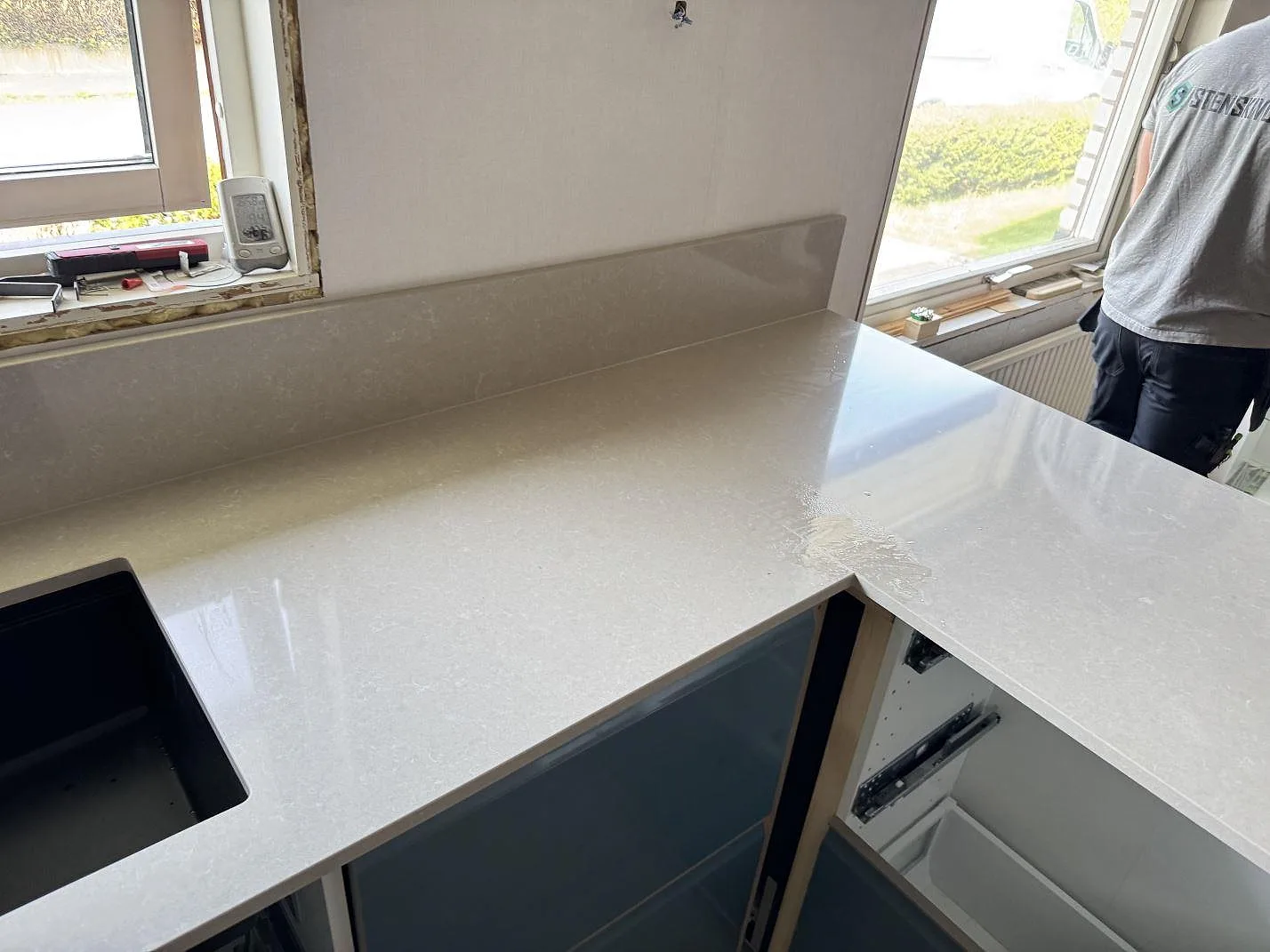 Topvy av polerad köksbänkskiva i Technistone Noble Ivory White med mörk diskho, hällurtag och stänkkant i Trollhättan.