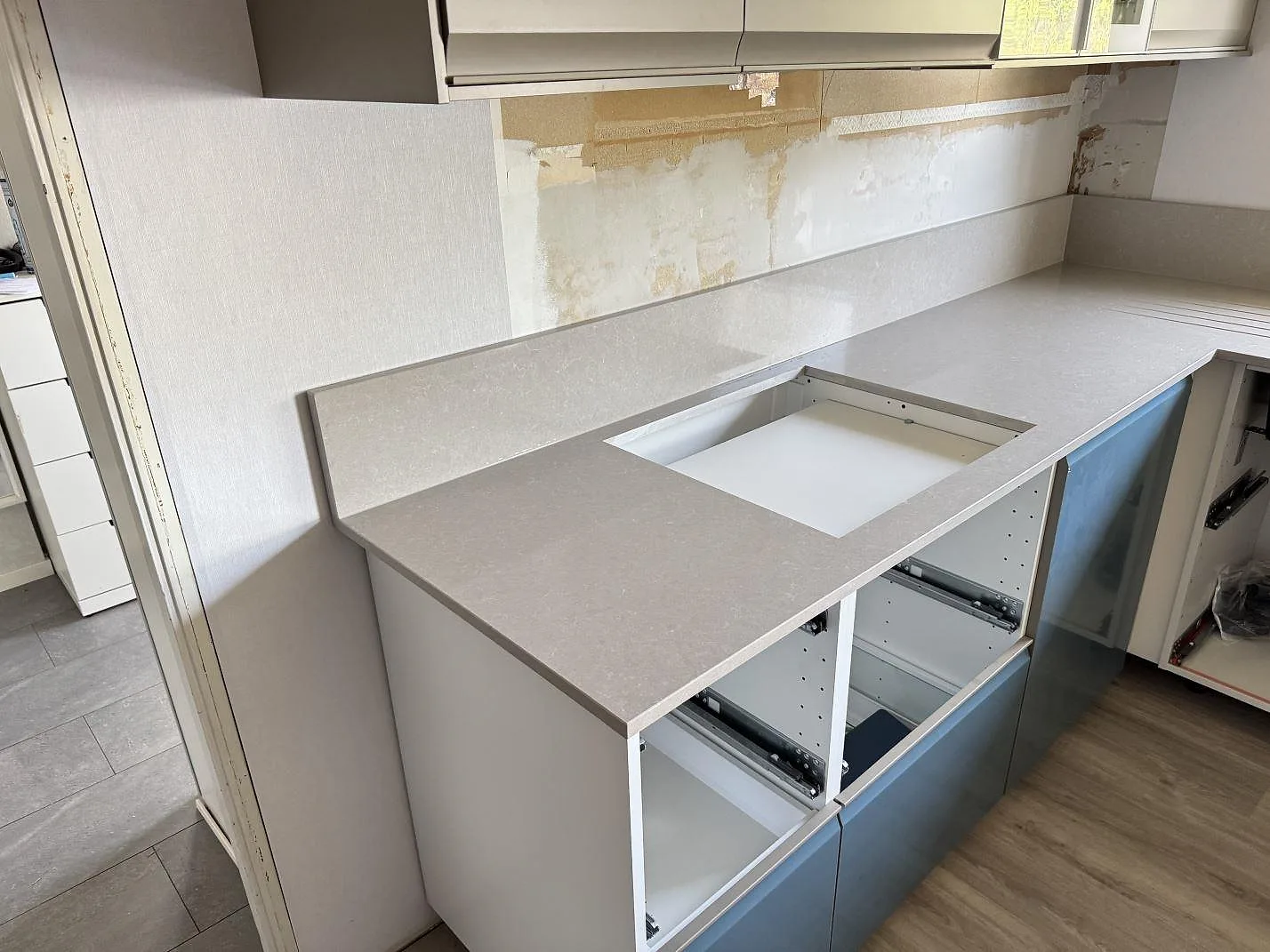 Installerad köksbänk i polerad Technistone Noble Ivory White med hällurtag och uppvikt stänkkant under montering i Trollhättan.