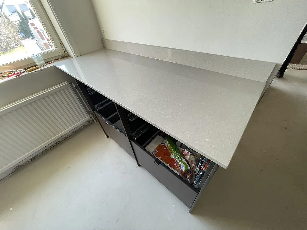 Polerad bänkskiva i Technistone Noble Ivory White komposit vid fönster med uppvikt stänkkant i ett kök i Tyresö.