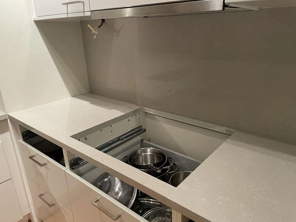 Urtag i polerad Technistone Noble Ivory White köksbänkskiva, kvartskomposit, med öppen låda under montering i Uppsala.