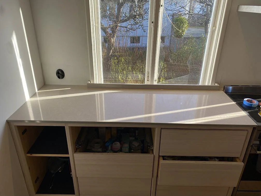 Polerad köksbänkskiva i Technistone Noble Ivory White vid fönster i ett kök i Västra Frölunda.