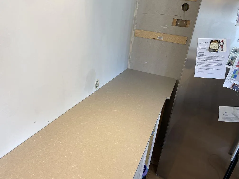 Sidobänk i Technistone Noble Ivory White, polerad kvartskomposit, intill kyl och vägg i kök i Västra Frölunda.