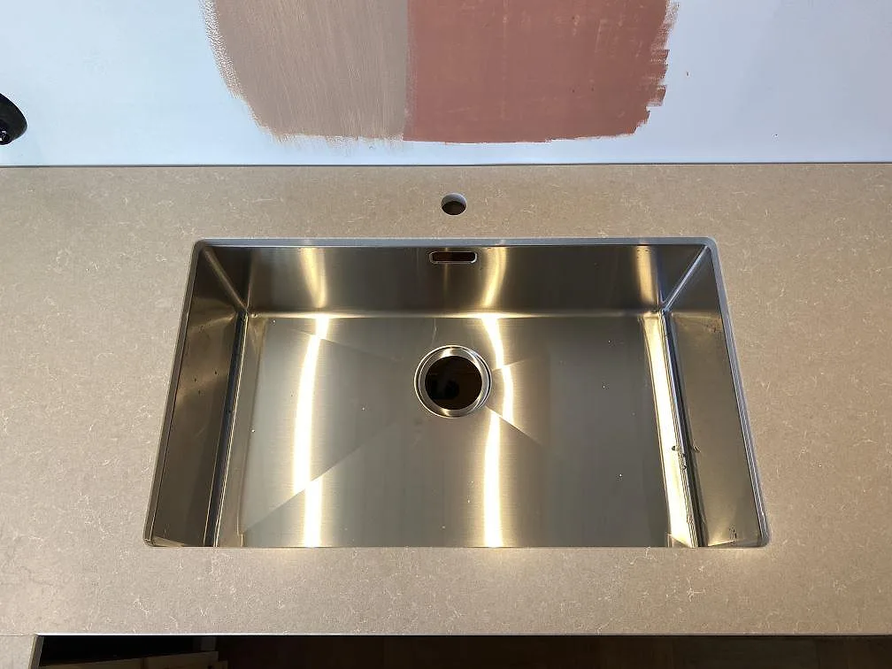 Detalj av rostfri diskho i bänkskiva av polerad Technistone Noble Ivory White i Västra Frölunda.