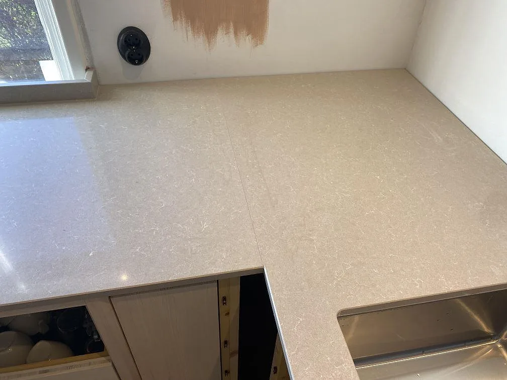 Hörndel av köksbänkskiva i Technistone Noble Ivory White med rostfri diskho och diskret mönstring i Västra Frölunda.