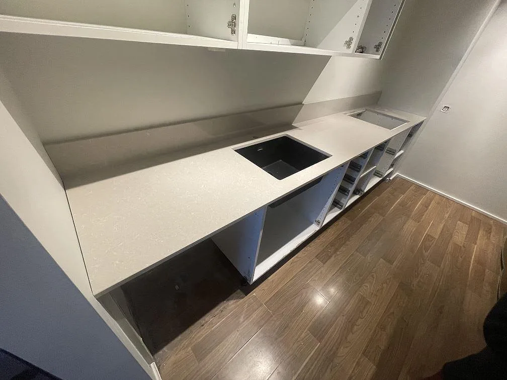 Polerad kvartskomposit Technistone Noble Ivory White på köksbänk med svart diskho och hällöppning vid öppna stommar i Vallentuna.