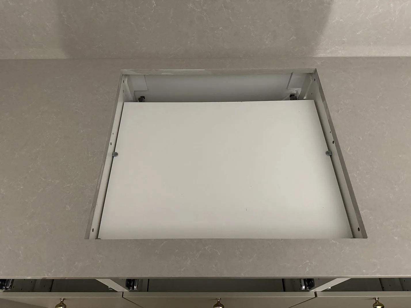 Detalj av hälluttag i polerad Technistone Noble Ivory White med stänkskydd bakom köksbänken i Vellinge.
