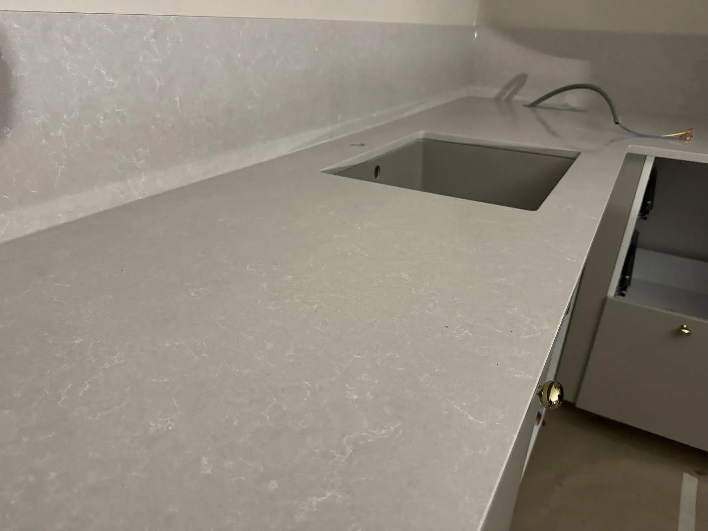 Polerad kompositbänkskiva i Technistone Noble Ivory White med underlimmad rostfri diskho och uppvikt stänkkant i Vellinge.