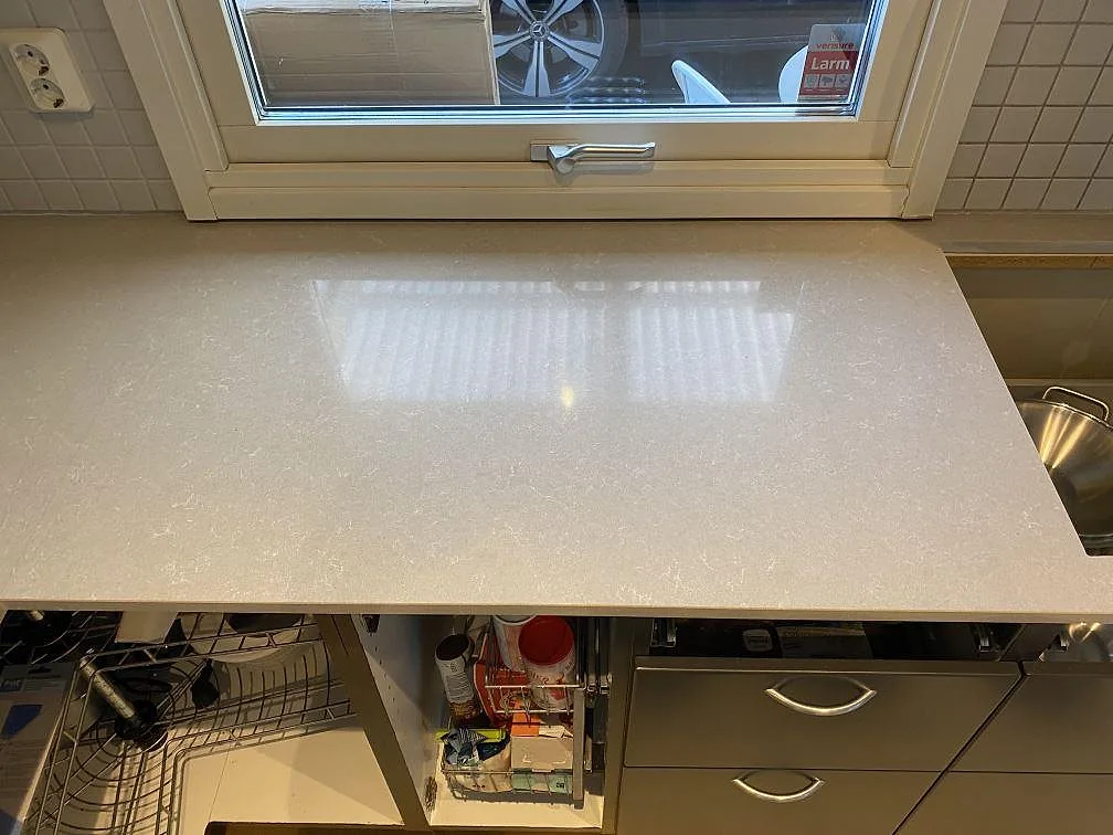 Köksbänkskiva under fönster i polerad Technistone Noble Ivory White, ljus kvartskomposit, med glansig yta i Vellinge.