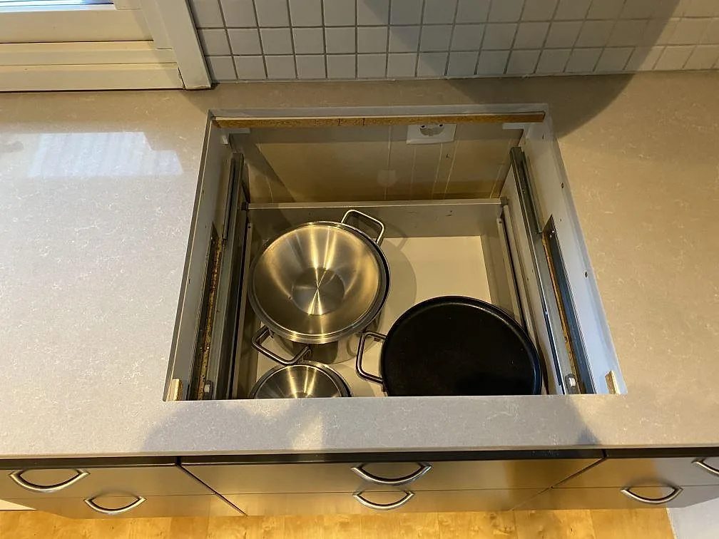 Polerad köksbänkskiva i Technistone Noble Ivory White, ljus kvartskomposit, runt öppen förvaring under arbetsytan i Vellinge.