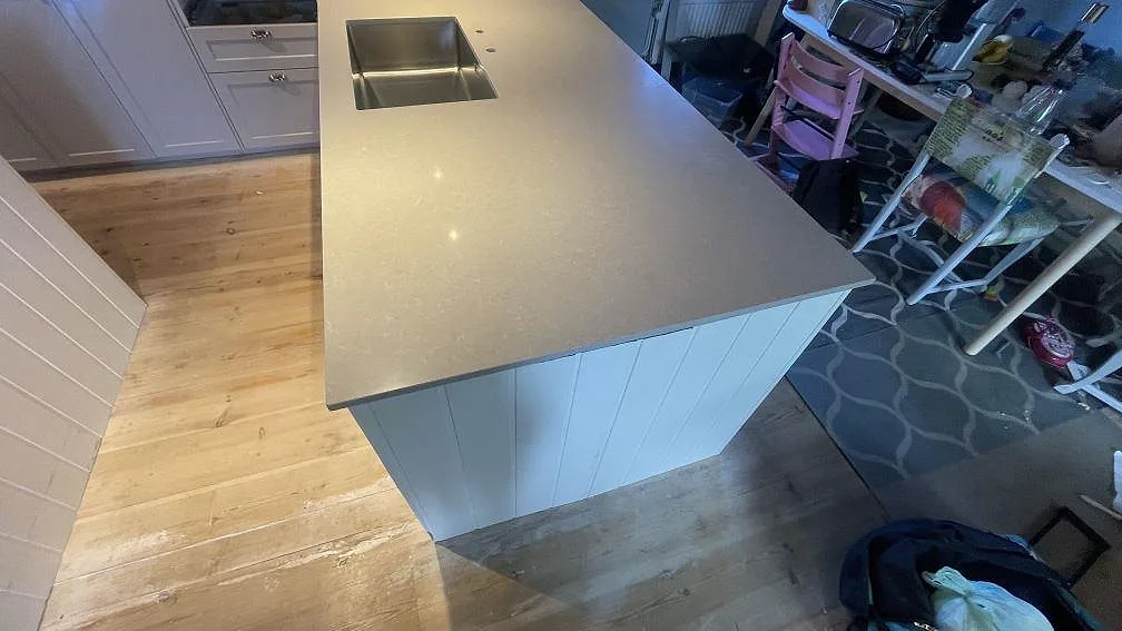 Närbild på köksö med bänkskiva i polerad Technistone Noble Ivory White, komposit, och diskho i Vellinge.