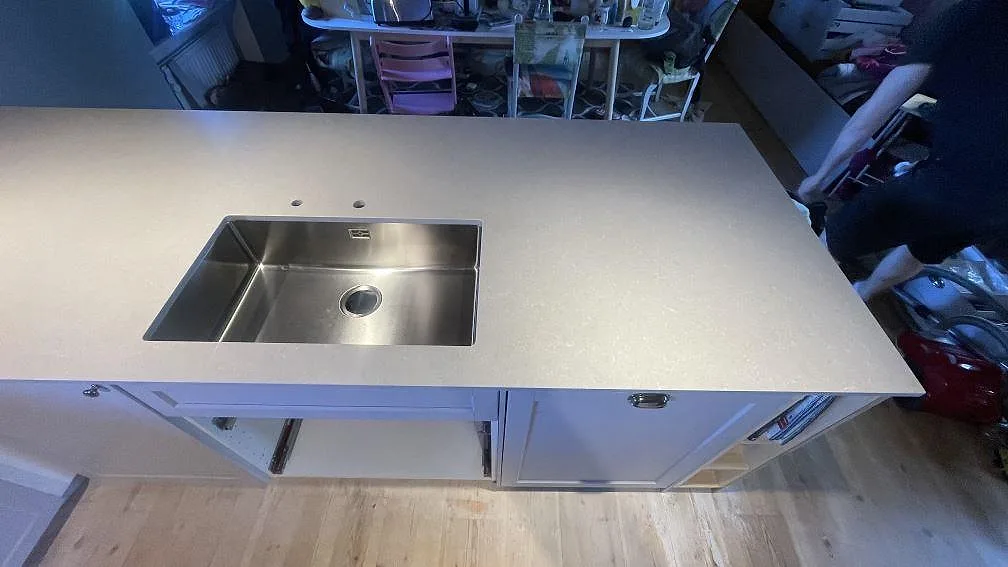 Detalj av köksbänkskiva i polerad Technistone Noble Ivory White, komposit, runt diskho i ett kök i Vellinge.