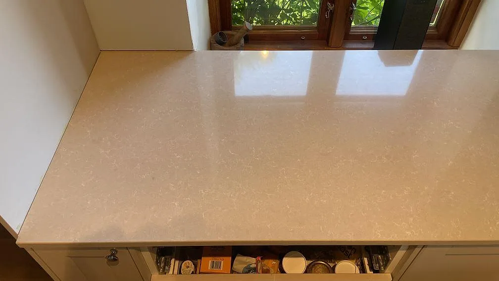 Detalj av polerad kompositbänkskiva i Technistone Noble Ivory White vid fönster i ett kök i Vellinge.