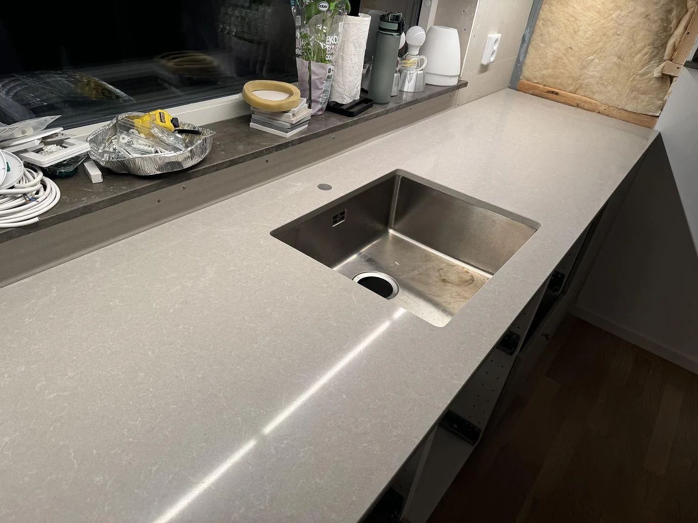 Polerad Technistone Noble Ivory White som köksbänkskiva med underlimmad rostfri diskho och blandarhål vid fönstret i Vintrie.