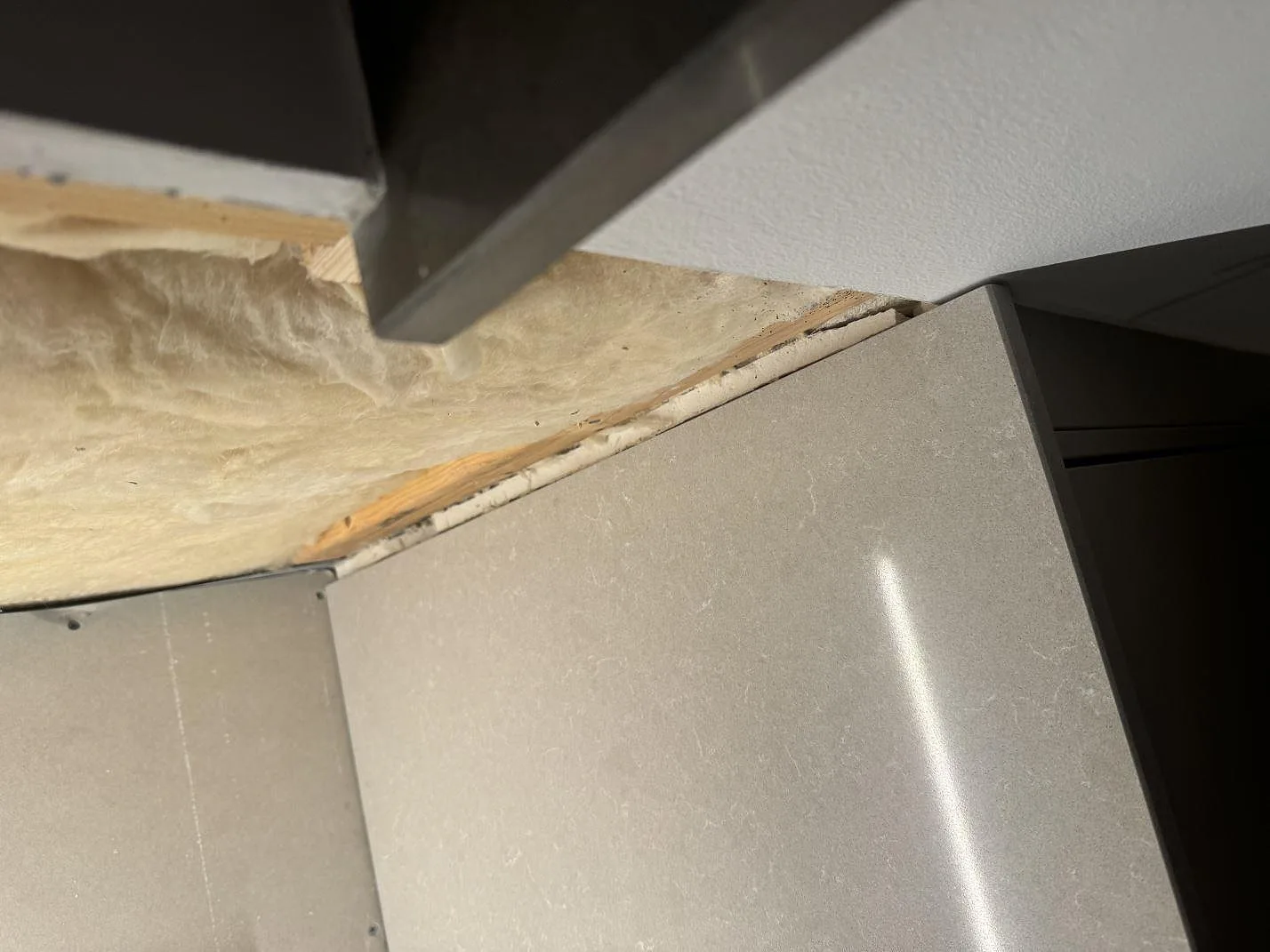 Detalj av polerad Technistone Noble Ivory White vid vägganslutning och köksstomme under montering i Vintrie.