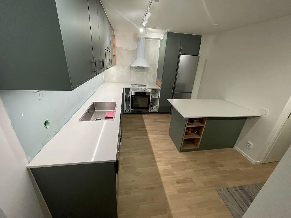 Polerad köksbänkskiva i Technistone Noble Linea med synlig diskho och separat köksö under montering i Solna.