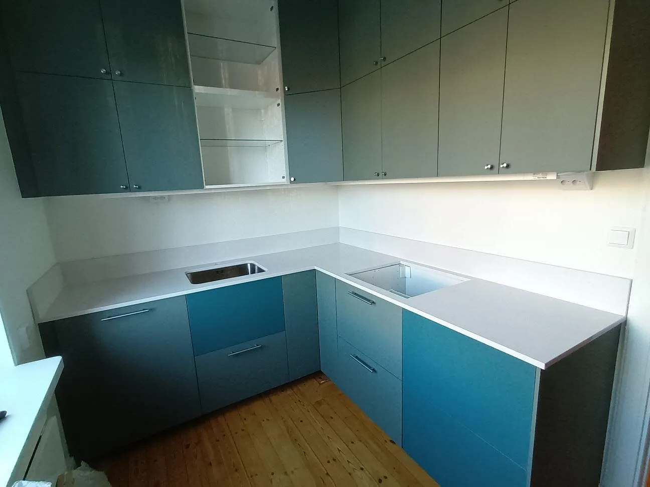 Köksbänkskiva i ljus Technistone Noble Linea, polerad komposit, med underlimmad rostfri diskho och hällurtag i ett kök i Uppsala.
