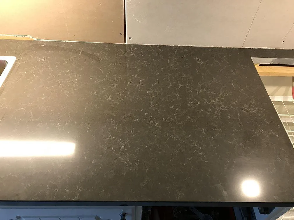Polerad köksbänkskiva i Technistone Noble Pietra Grey sedd uppifrån, med mjuk grå ådring och inbyggd rostfri diskho, i ett kök i Fjärås.