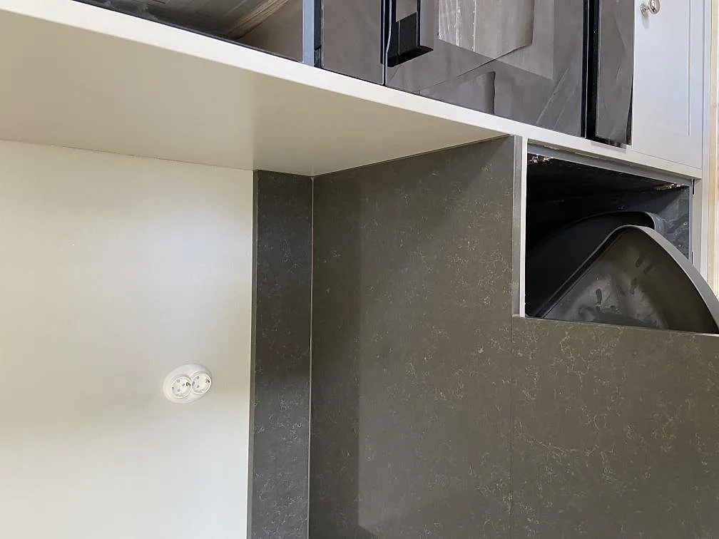 Hörn av grå Technistone Noble Pietra Grey bänkskiva med uppvikt stänkkant i samma sten i ett kök i Göteborg.