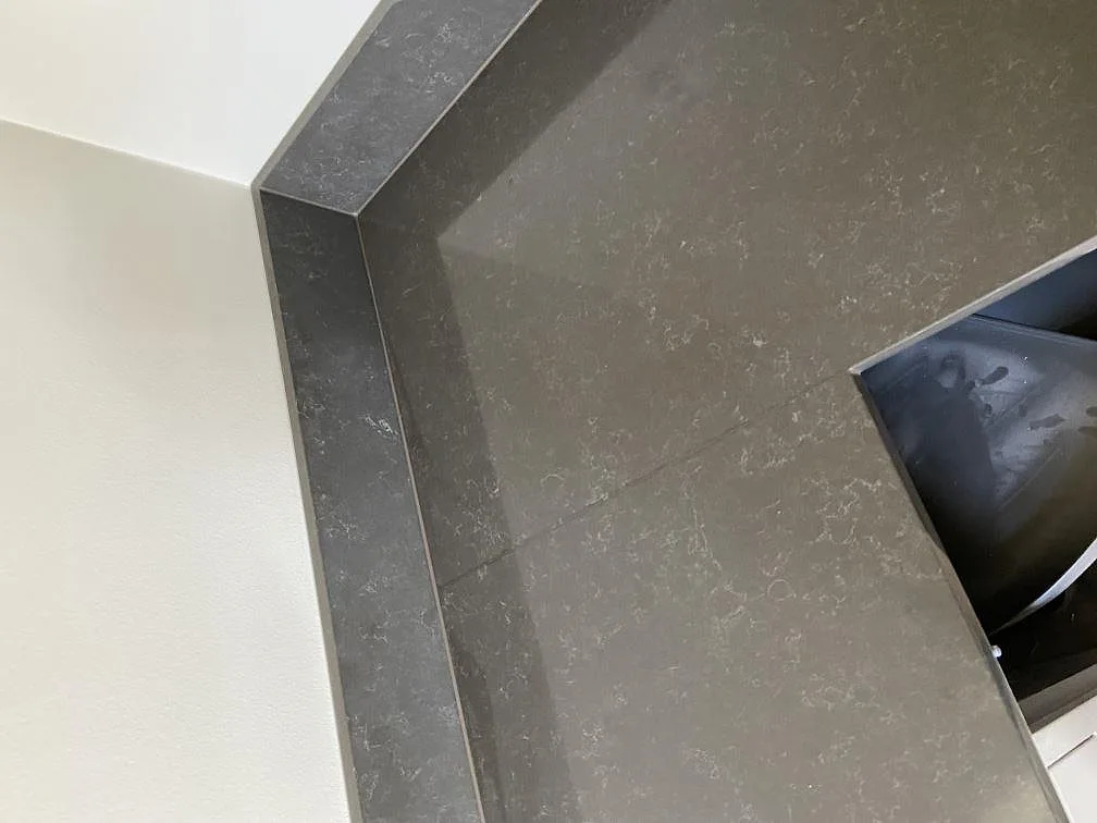 Närbild på den mjuka diskreta ådringen i polerad grå Technistone Noble Pietra Grey kvartskomposit med uppvikt stänkkant i ett kök i Göteborg.