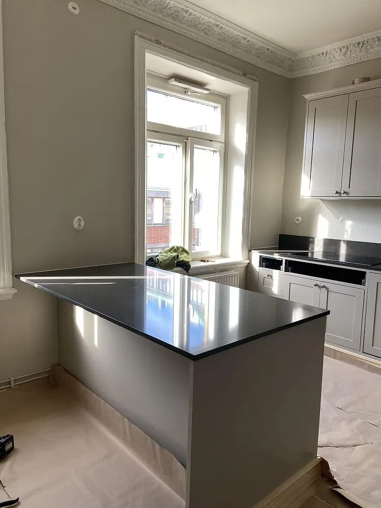 Grå Technistone Noble Pietra Grey bänkskiva på en köksö framför fönster i ett kök i Göteborg, taget under montering.