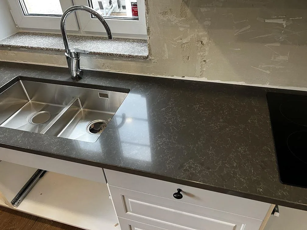 Köksbänkskiva i mörk Technistone Noble Pietra Grey med rostfri diskho, blandare och synlig häll i Hästveda.