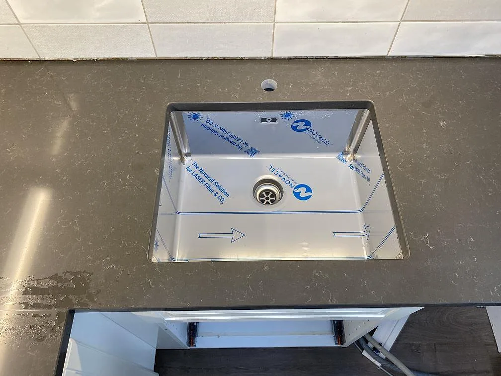 Diskhoområdet i en polerad Technistone Noble Pietra Grey bänkskiva med blandarhål, grå komposit i ett kök i Kungsbacka.