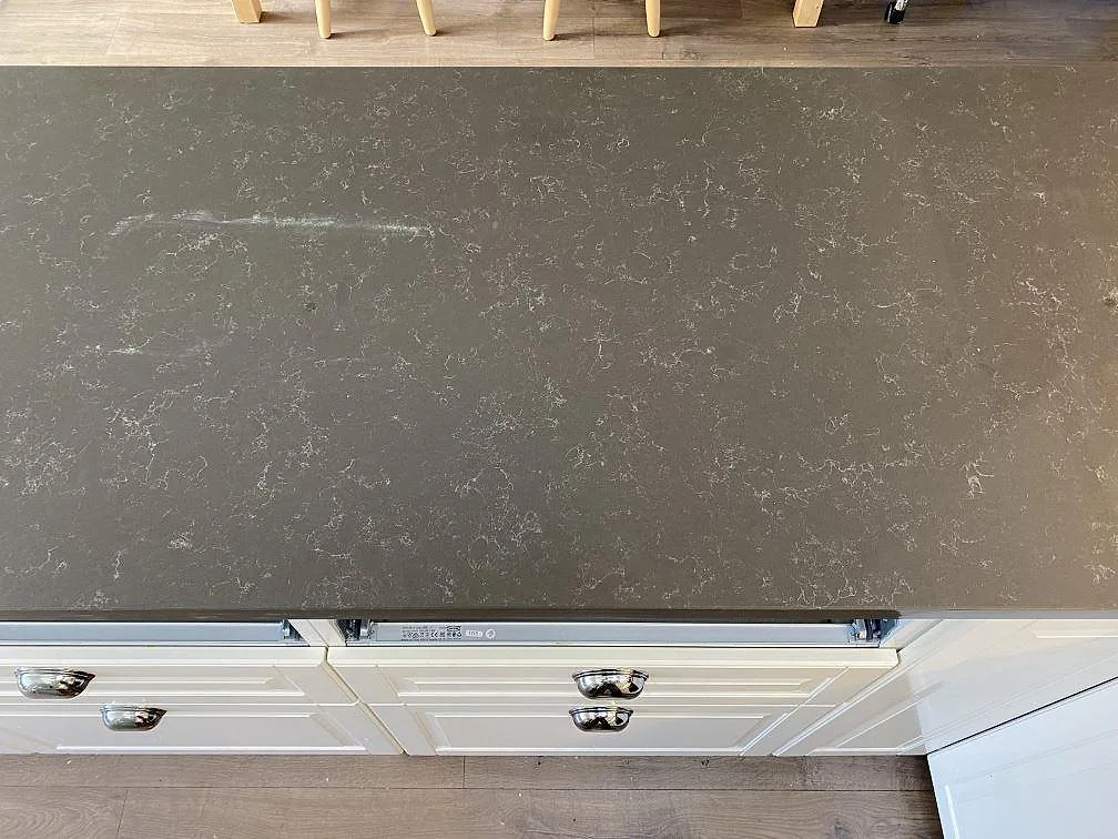 Polerad Technistone Noble Pietra Grey köksbänkskiva i grå komposit ovanpå vita köksskåp i Kungsbacka.