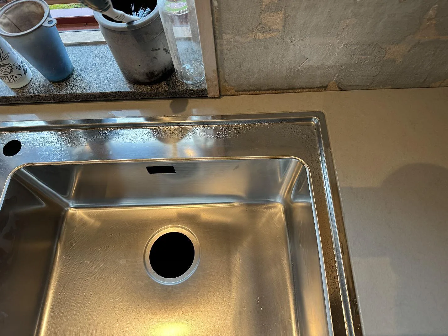 Köksbänkskiva i polerad Technistone Noble Portland Grey komposit med diskho och fönsternisch under montering i Ellös.