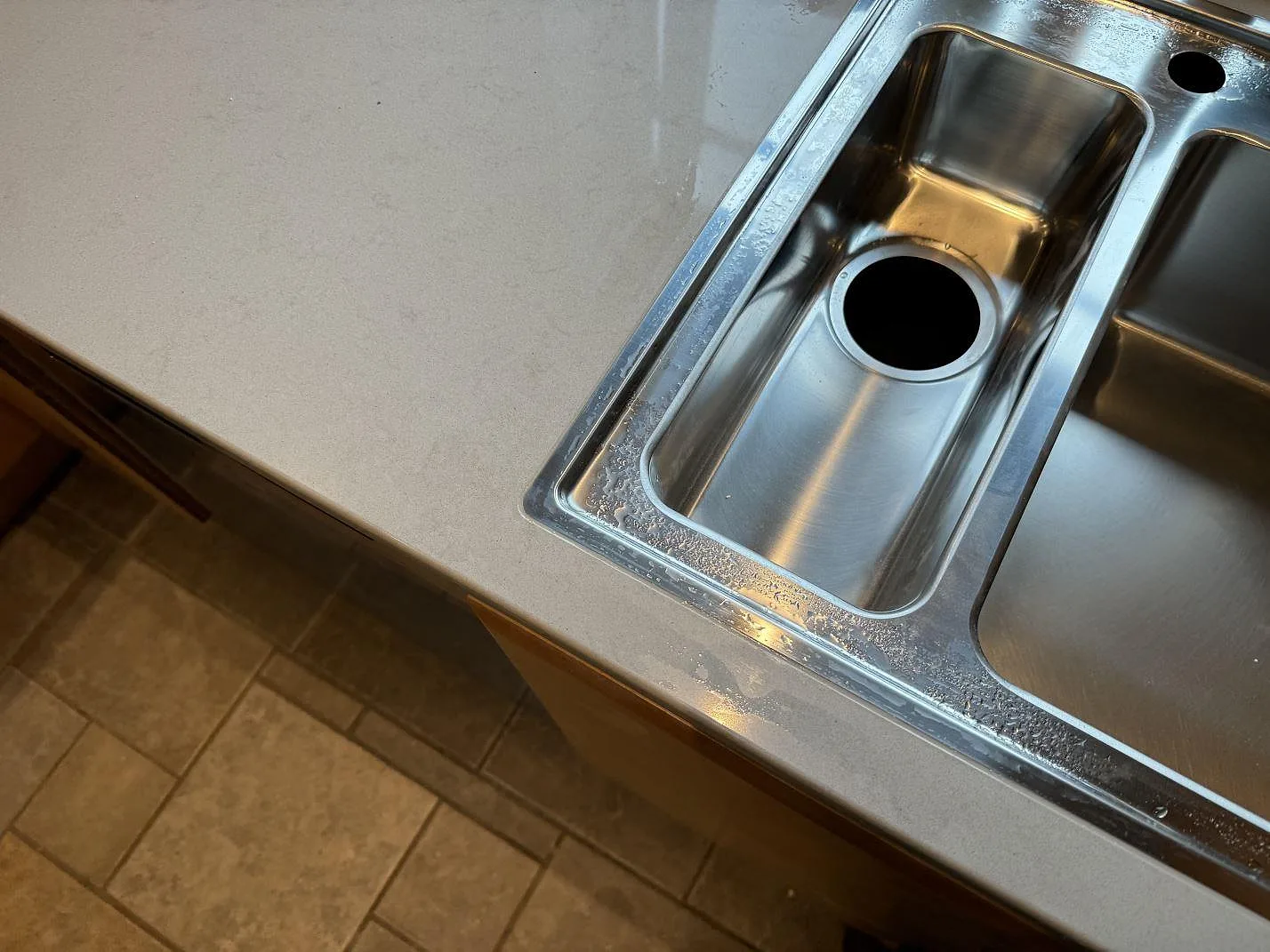Närbild av rostfri dubbelho och polerad Technistone Noble Portland Grey komposit i kök i Ellös.