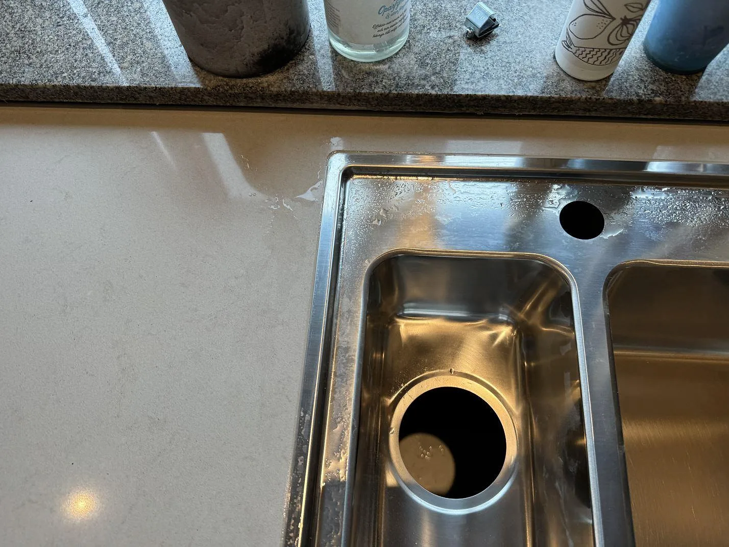 Polerad Technistone Noble Portland Grey komposit runt rostfri diskho och fönsterbräda i ett kök i Ellös.
