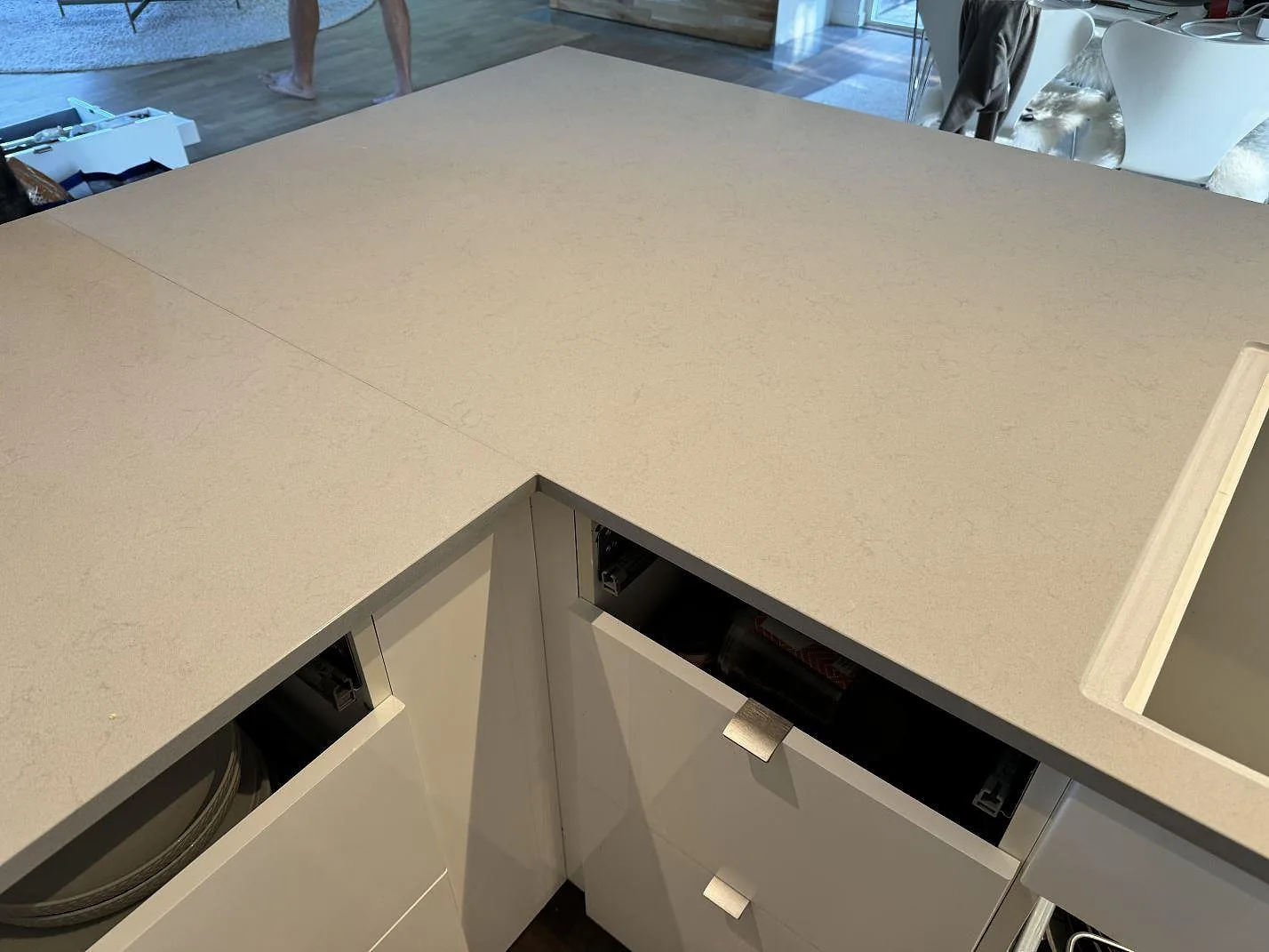 Hörndel av köksbänkskiva i polerad Technistone Noble Portland Grey komposit under montering i ett kök i Räng.