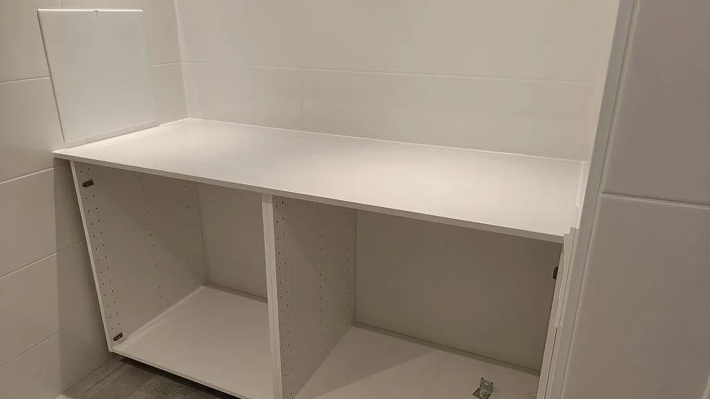 Lång vit bänkskiva i Technistone Noble Pro Frost monterad ovanpå öppna stommar, polerad kvartskomposit i ett grovkök i Jönköping.