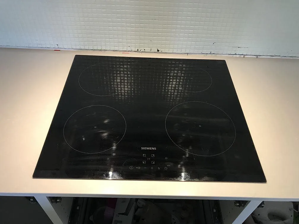 Infälld svart Siemens-häll i en bänkskiva av vit Technistone Noble Pro Frost med vitt mosaikkakel bakom i ett kök i Limhamn.