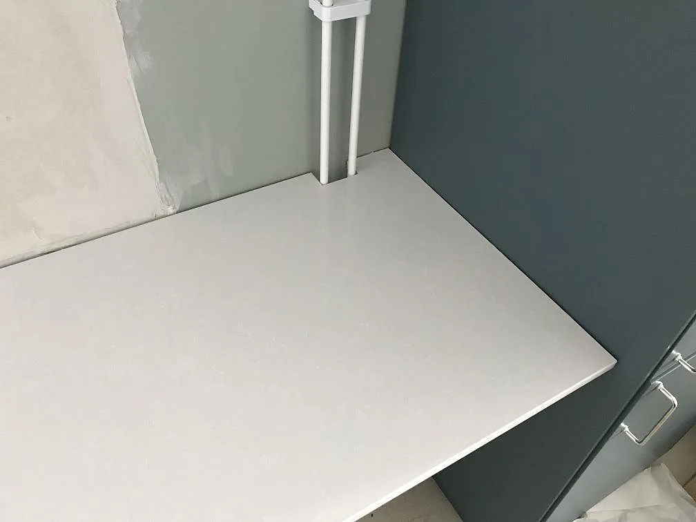 Returdel av köksbänkskivan i Technistone Noble Pro Frost mot blå köksstomme i ett kök i Limhamn.