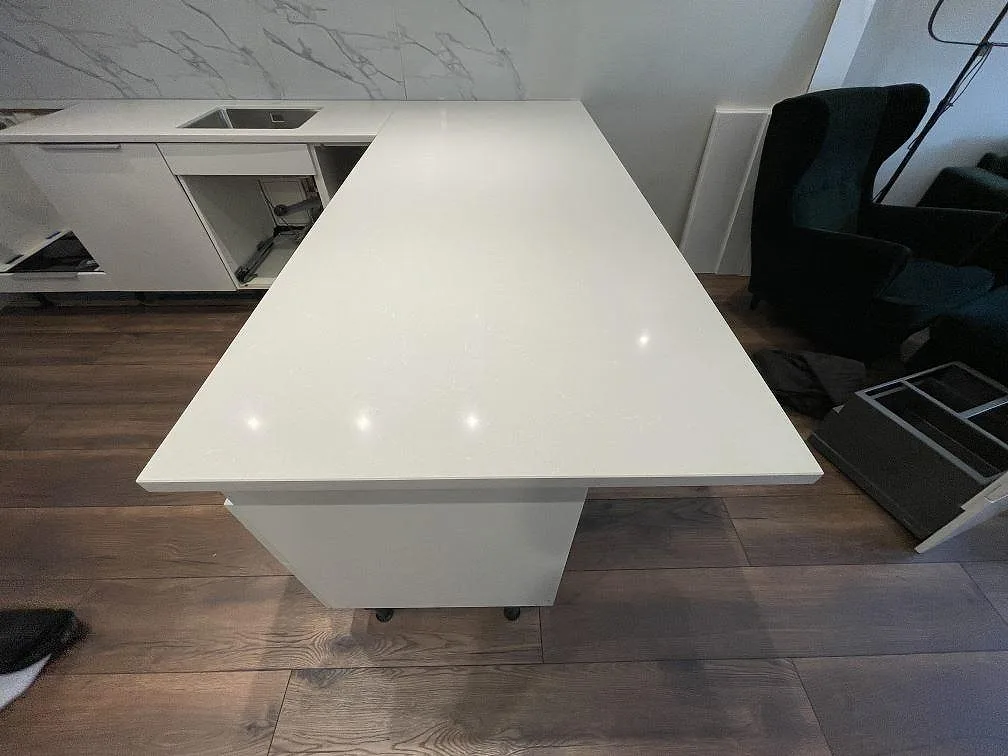 Stor arbetsyta i polerad Technistone Noble Pro Frost komposit framför köksrad med diskho i Sollentuna.