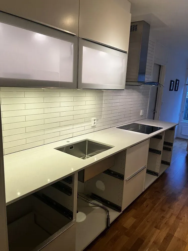 Köksbänkskiva i vit Technistone Noble Pro Frost, polerad kvartskomposit, med köksö, underlimmad rostfri diskho och induktionshäll i ett kök i Växjö.