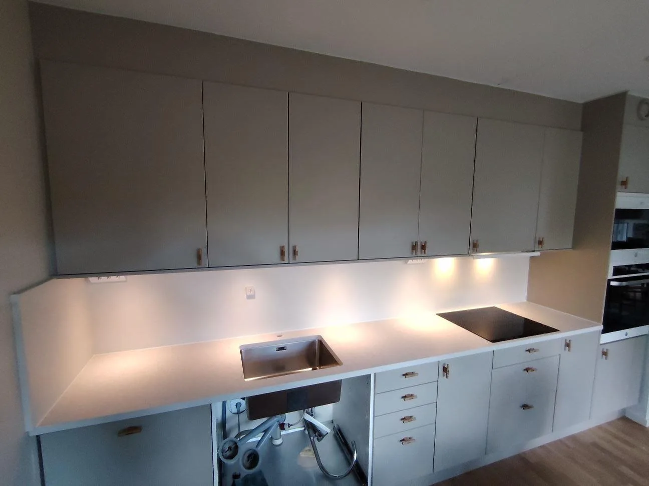 Köksbänkskiva i ljus Technistone Noble Quartzite, matt kvartskomposit, med diskho och häll i ett kök i Årsta.