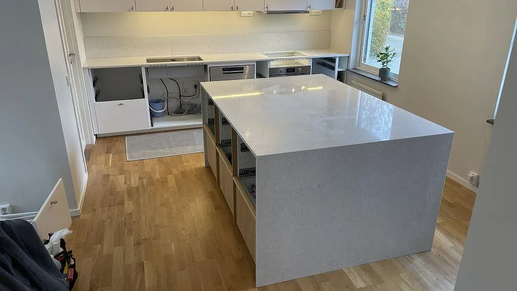 Köksbänkskiva i polerad Technistone Noble Quartzite, ljus kvartskomposit, med köksö, väggbänk och låg stänkkant i Bjärred.
