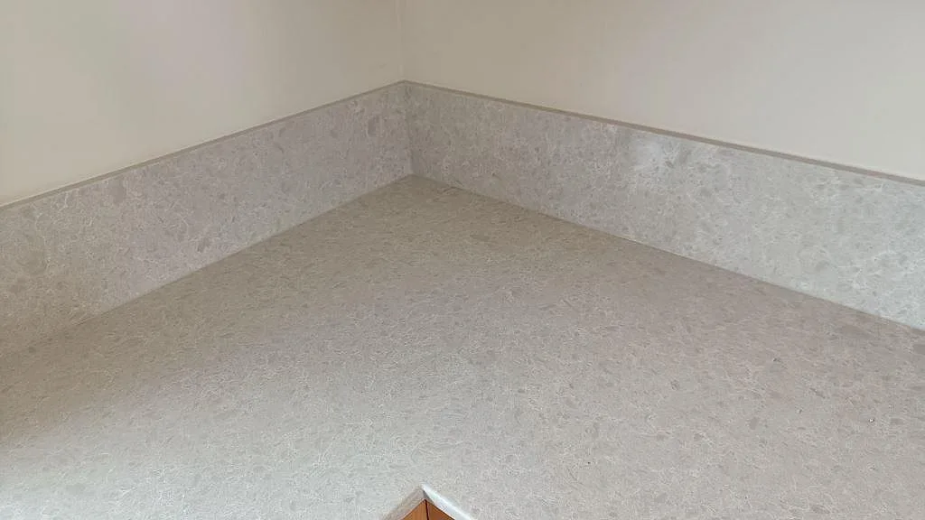 Hörnparti med polerad Technistone Noble Quartzite som bänkskiva och stänkkant i ett kök i Furulund.