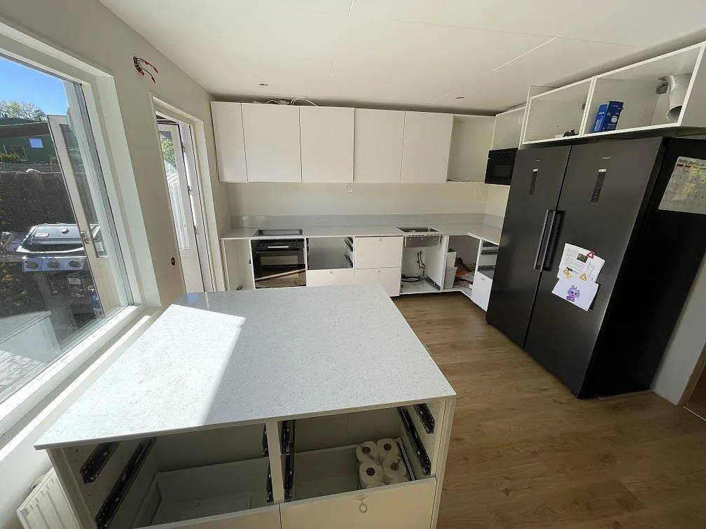 Översikt av kök under montering med polerad Technistone Noble Quartzite på köksö och väggbänk med låg stänkkant i Järfälla.