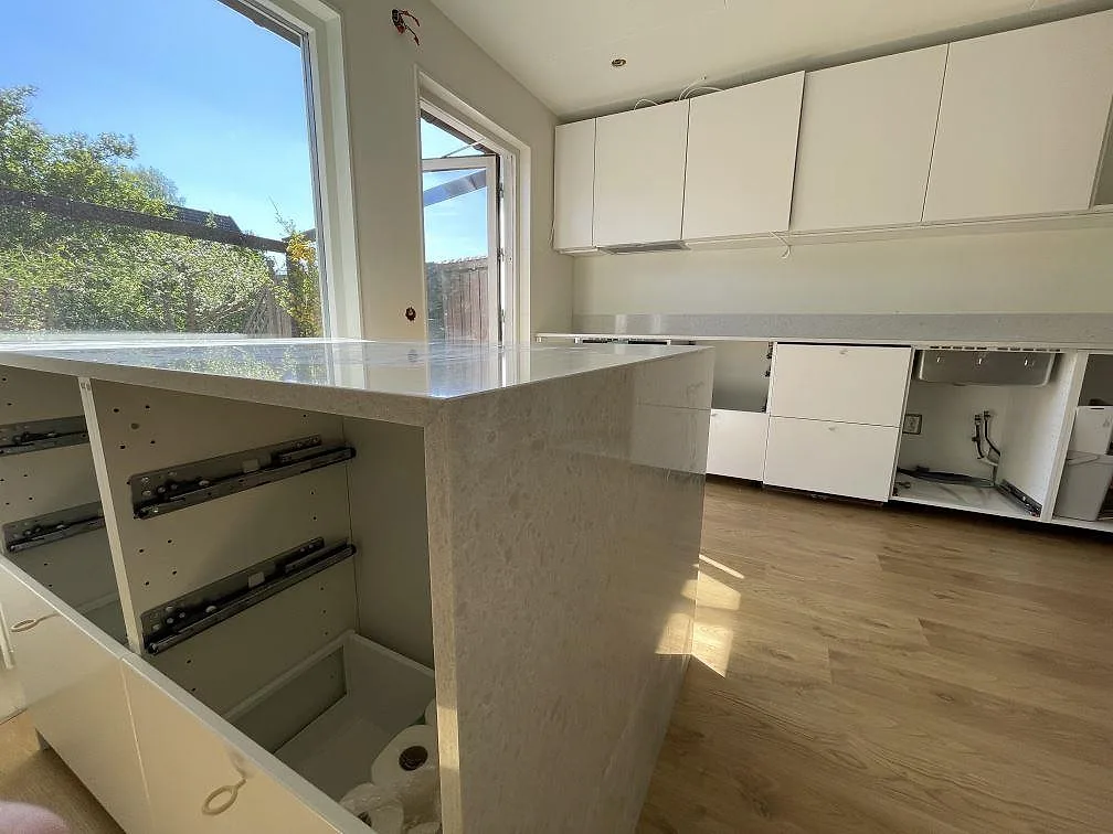Neddragen gavel och blank ovansida på köksö i polerad Technistone Noble Quartzite med väggbänk i bakgrunden i Järfälla.