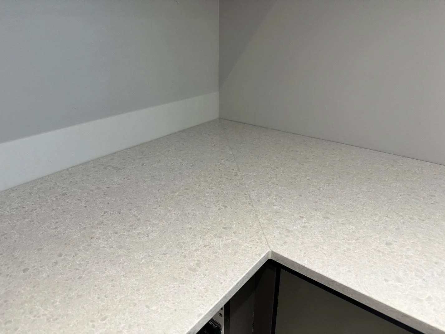 Detalj av hörnskarven i en L-formad köksbänkskiva av polerad Technistone Noble Quartzite i Malmö.