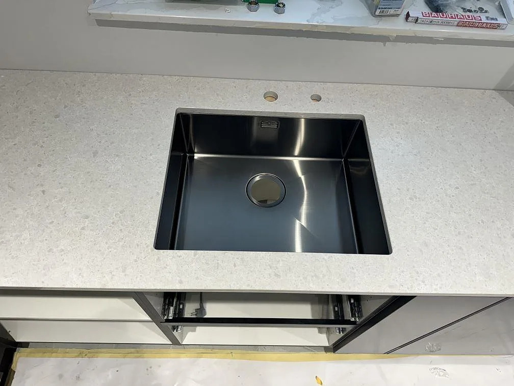 Närbild på svart underlimmad diskho i en 20 mm polerad Technistone Noble Quartzite bänkskiva i Malmö.